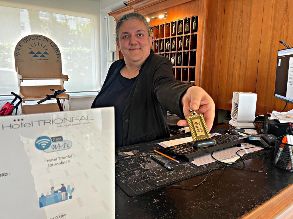 une femme assise à un bureau tenant un outil dans l'établissement HOTEL TRIONFAL - Fronte Mare - Vicinissimi al Centro, à Milano Marittima