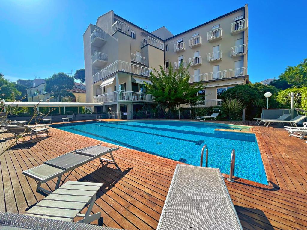 une piscine avec des chaises et un bâtiment dans l'établissement HOTEL TRIONFAL - Fronte Mare - Vicinissimi al Centro, à Milano Marittima