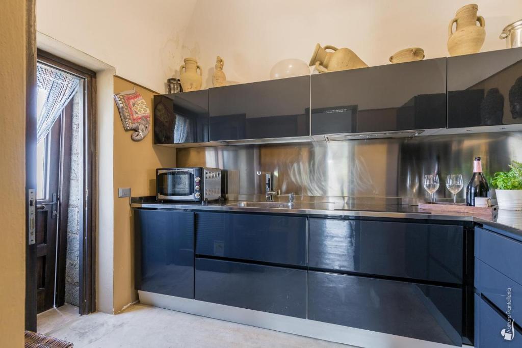 une cuisine avec des armoires noires et un four micro-ondes dans l'établissement Dammuso Taygeta, à Pantelleria