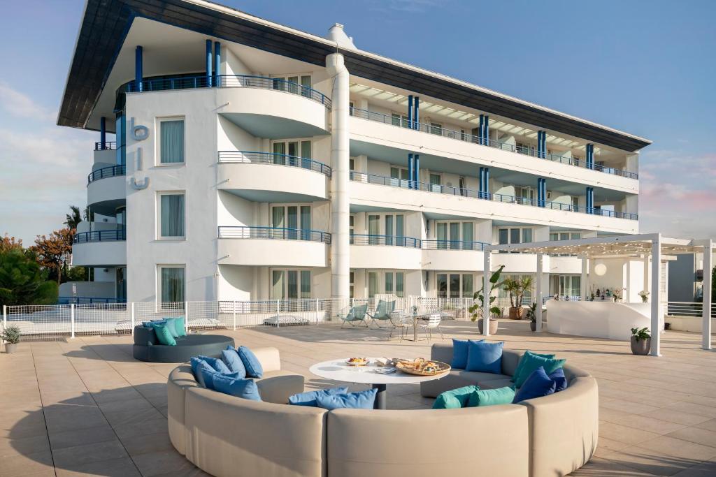 - un grand bâtiment blanc avec des canapés en face dans l'établissement Blu Suite Resort, à Bellaria-Igea Marina