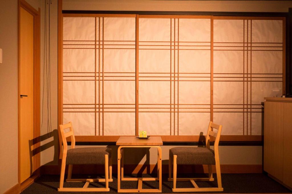 une table et des chaises dans une pièce avec une grande fenêtre dans l'établissement Ito Kowakien, à Itō