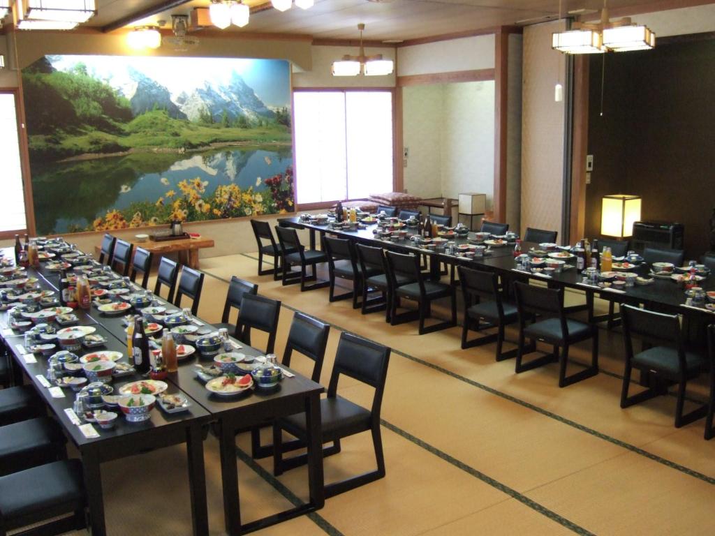une grande salle de conférence avec de longues tables et chaises dans l'établissement Shinseikan, à Nishiwaga