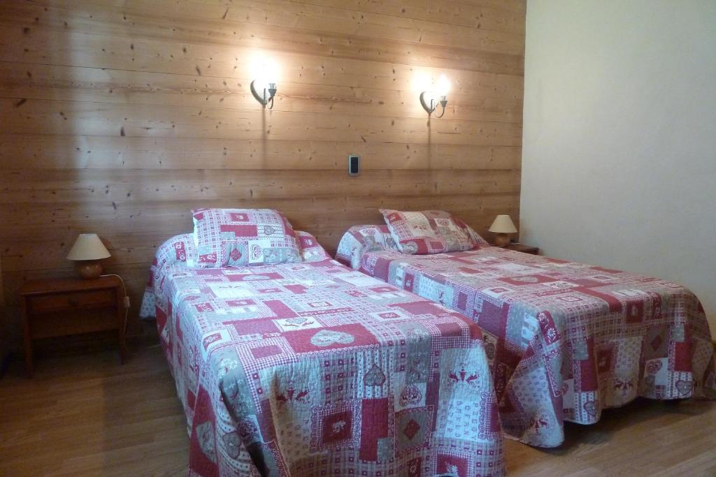 deux lits jumeaux dans une chambre aux murs en bois dans l'établissement Chalet "les Arcosses", à La Giettaz