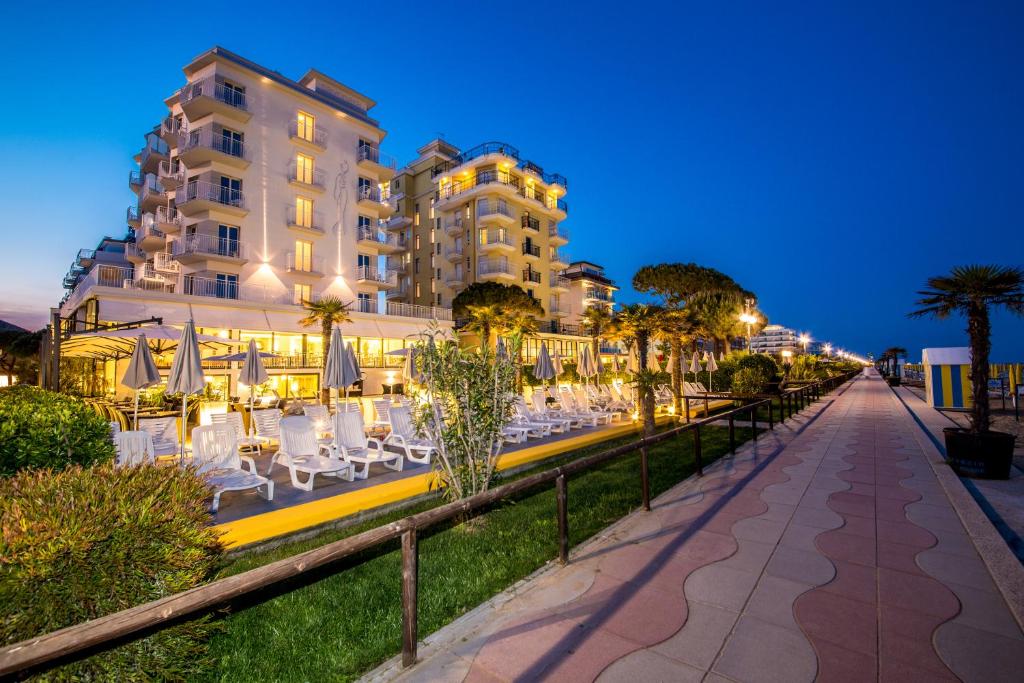 une rue avec des tables et des chaises devant un bâtiment dans l'établissement Hotel Sayonara, à Lido di Jesolo