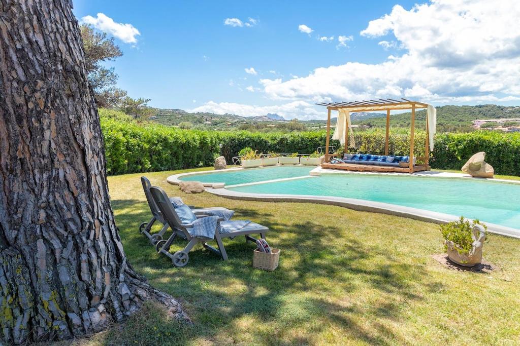 une chaise assise dans l'herbe à côté d'une piscine dans l'établissement Villa con piscina e giardino, à Cala Bitta