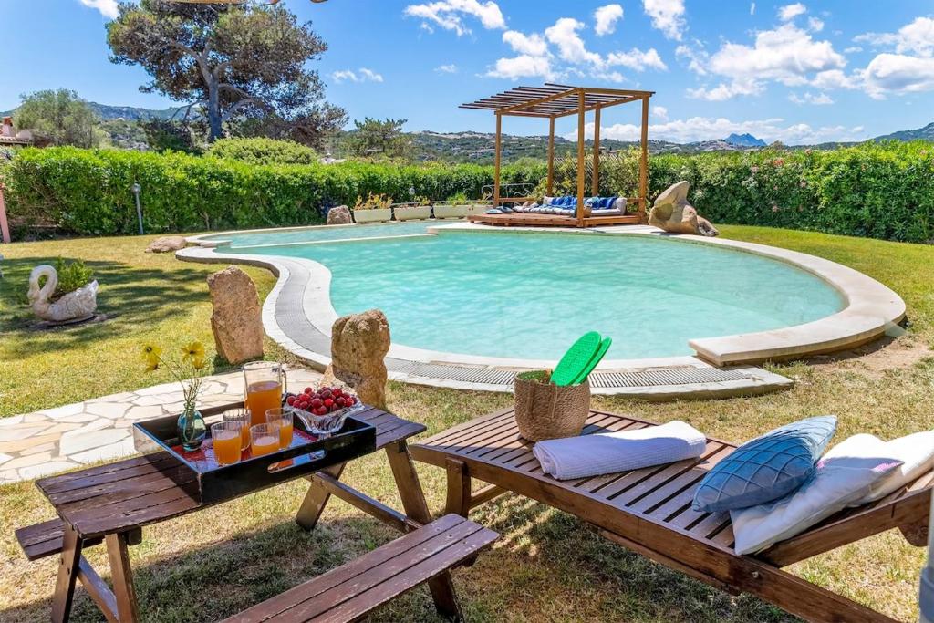 une piscine avec une table et une table de pique-nique avec un plateau de pique-nique dans l'établissement Villa con piscina e giardino, à Cala Bitta