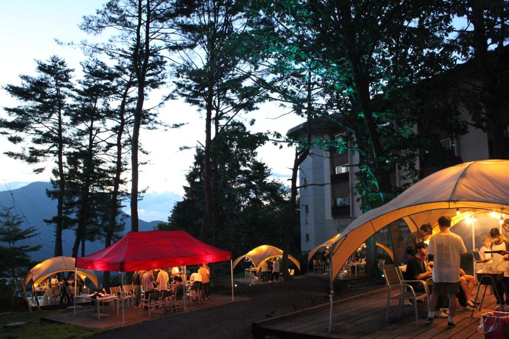 Un groupe de personnes assises à des tables sous des parasols dans l'établissement Kitashiga Holiday Inn, à Yamanouchi