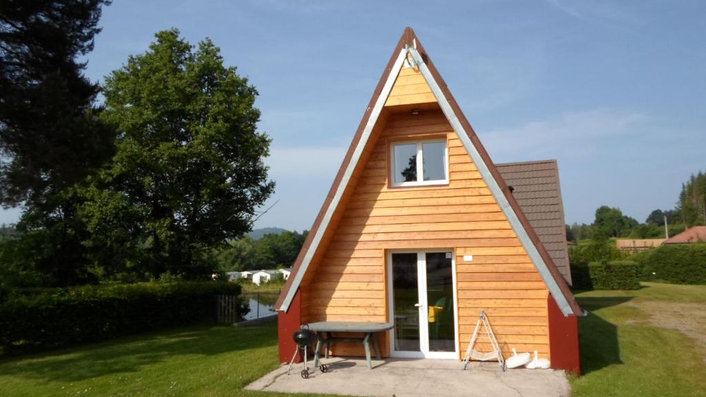 une petite maison avec un toit mansardé dans l'établissement Camping les Pinasses, à La Chapelle