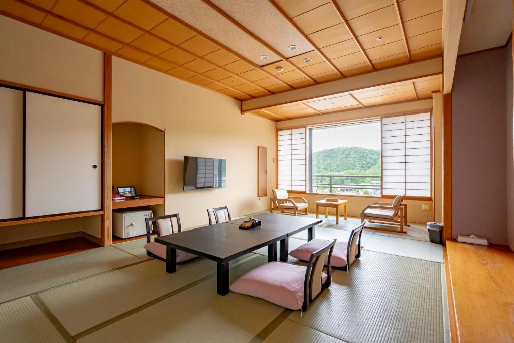 - un salon avec une table, des chaises et une grande fenêtre dans l'établissement Rantei, à Sendai