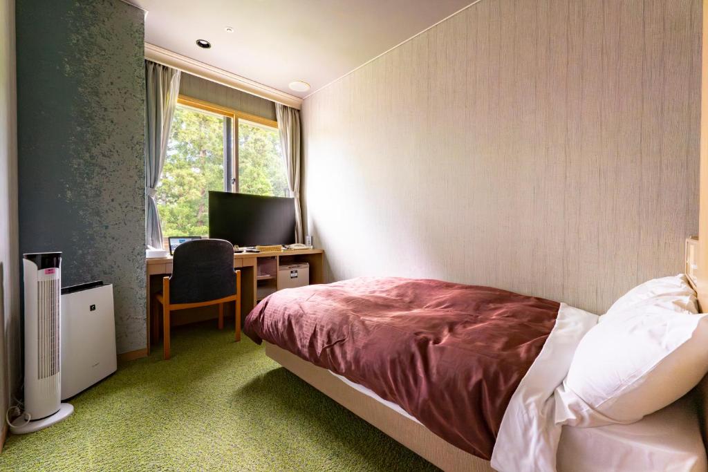une chambre avec un lit et un bureau avec un ordinateur dans l'établissement Rantei, à Sendai