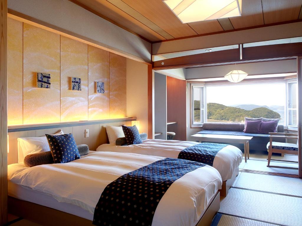 deux lits dans une chambre avec une grande fenêtre dans l'établissement Sun Urashima Yuki no Sato, à Toba