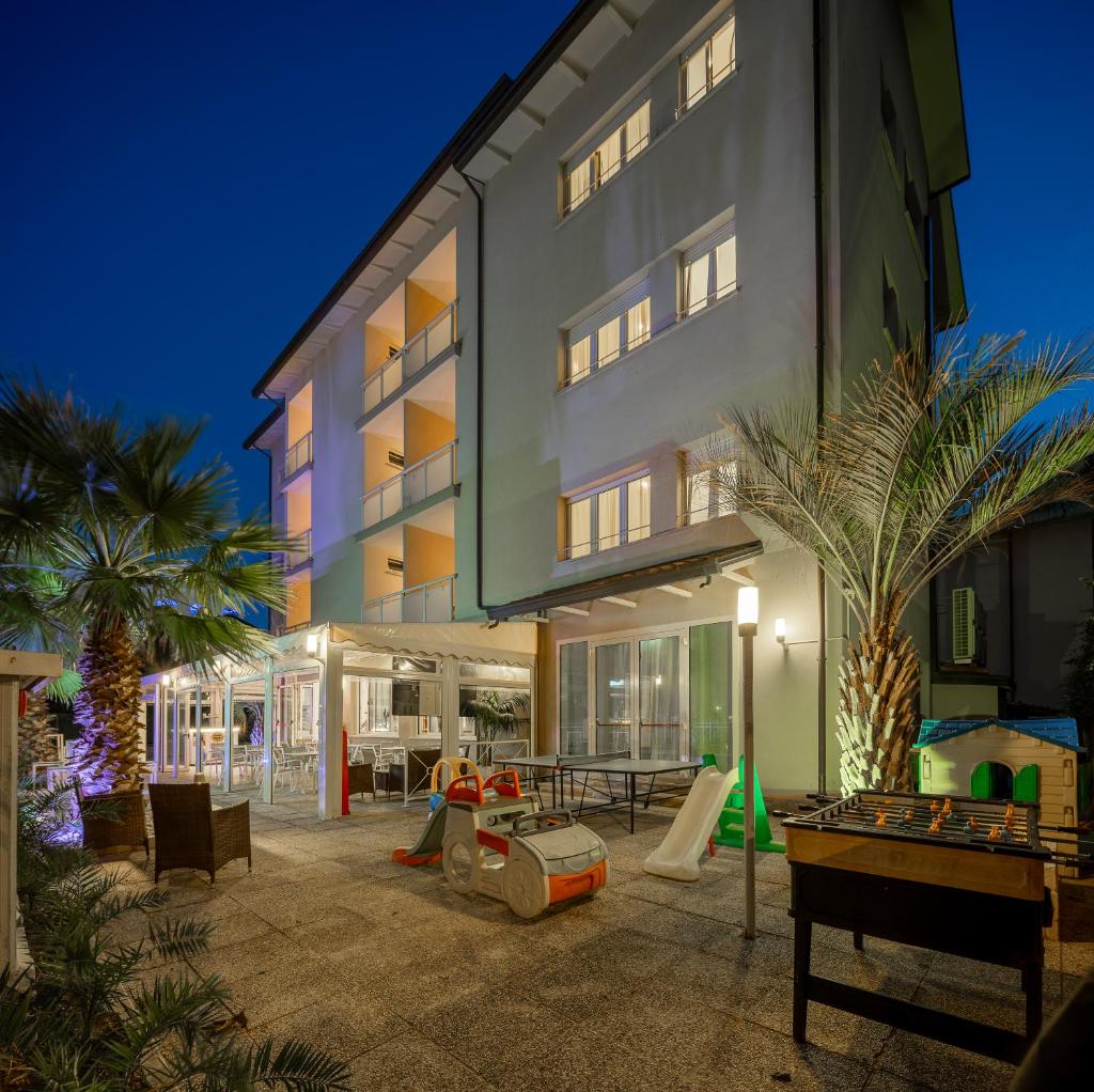 un immeuble d'appartements avec une aire de jeux en face dans l'établissement Hotel Altamarea Cesenatico, à Cesenatico