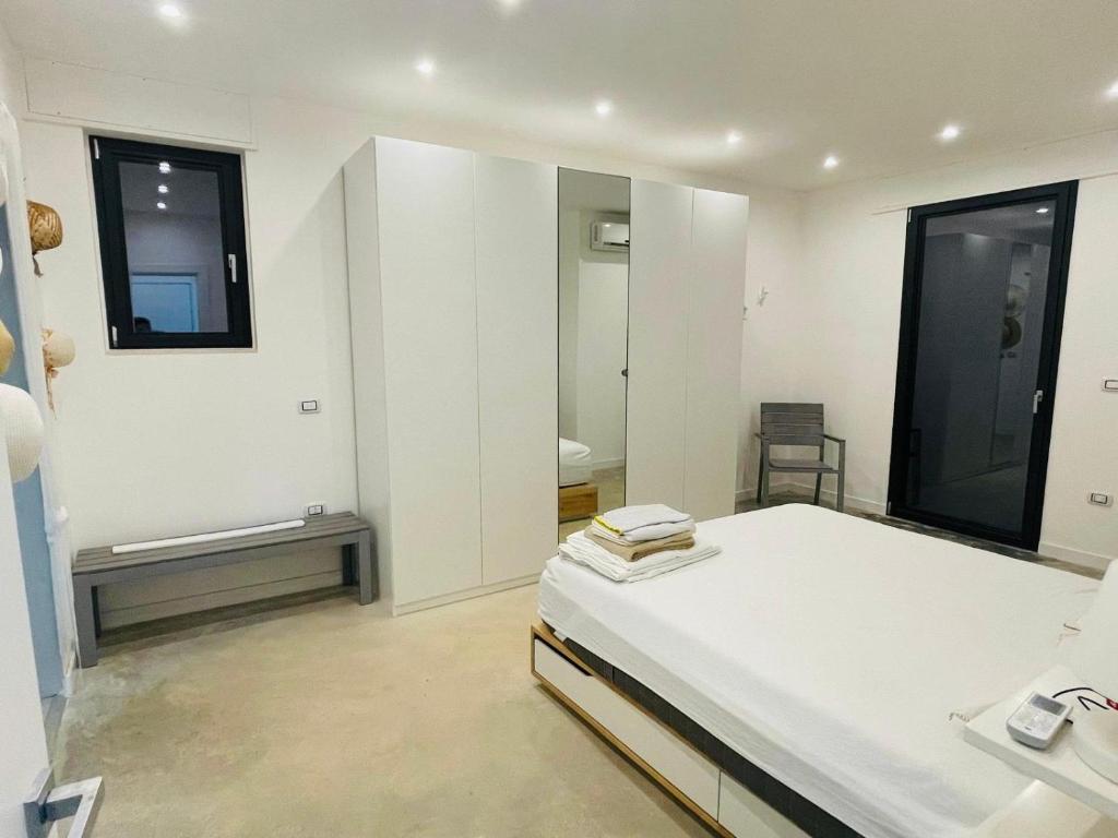 Cette chambre blanche comprend un lit et un miroir. dans l'établissement Villa degli Ulivi, à Torre Vado