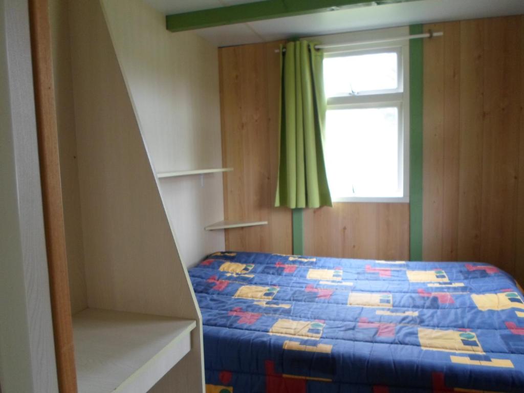 une petite chambre avec un lit et une fenêtre dans l'établissement Camping les Pinasses, à La Chapelle