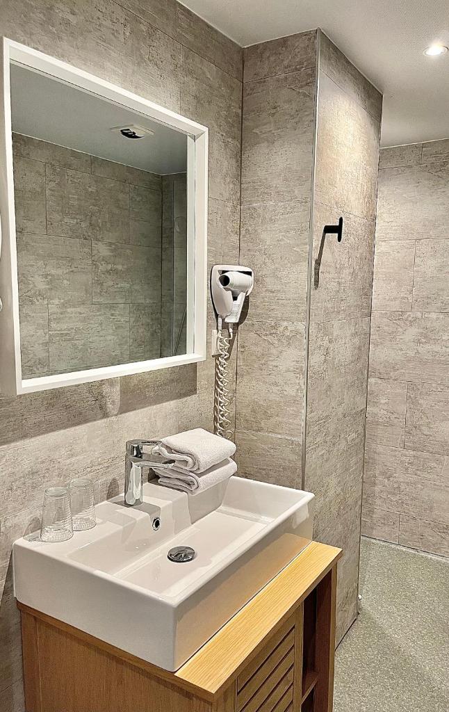 une salle de bain avec un lavabo blanc et un miroir dans l'établissement Hotel le Sacca, nouvelle équipe, à Cauterets 37 autres photos