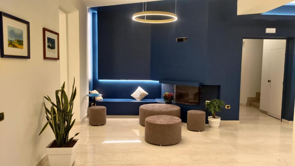 un hall d'entrée avec un mur bleu avec un canapé et des tabourets dans l'établissement Hotel Il Caminetto, à Porto San Giorgio