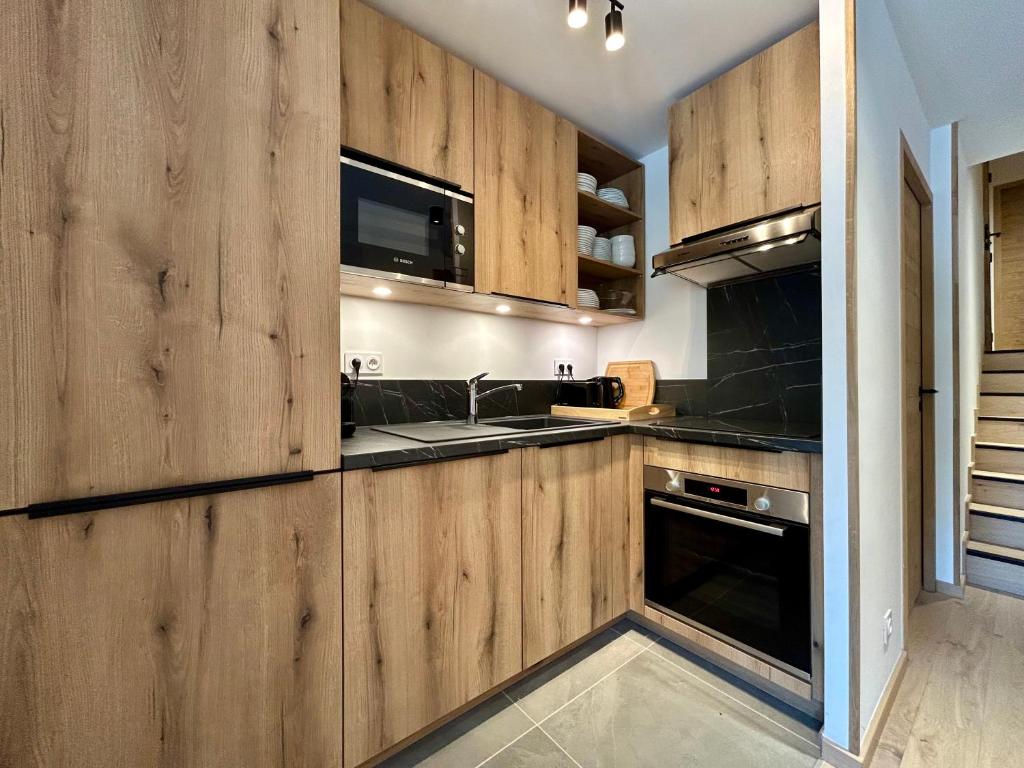 une cuisine avec des armoires en bois et un évier dans l'établissement Homency - Résidence L'Expression B12, à L'Alpe-d'Huez