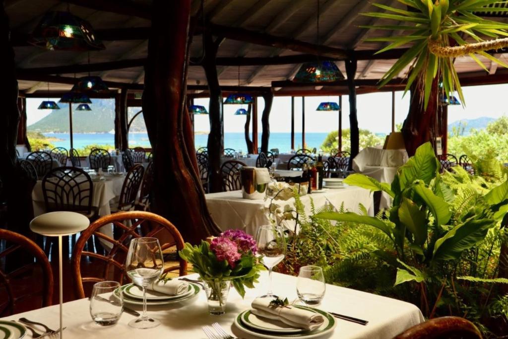 un restaurant avec des tables et des chaises avec l'océan en arrière-plan dans l'établissement Hotel Don Diego, à Porto San Paolo