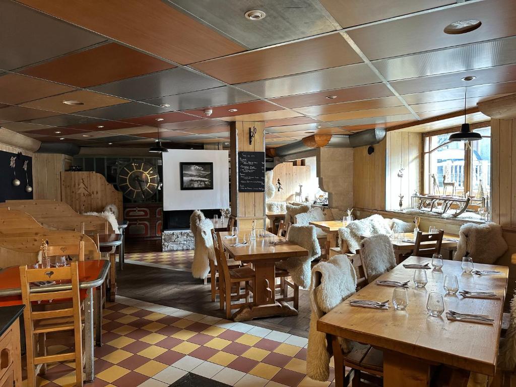 un restaurant avec des tables et des chaises dans une salle dans l'établissement Hôtel-Chalet les Mélèzes, à Valloire