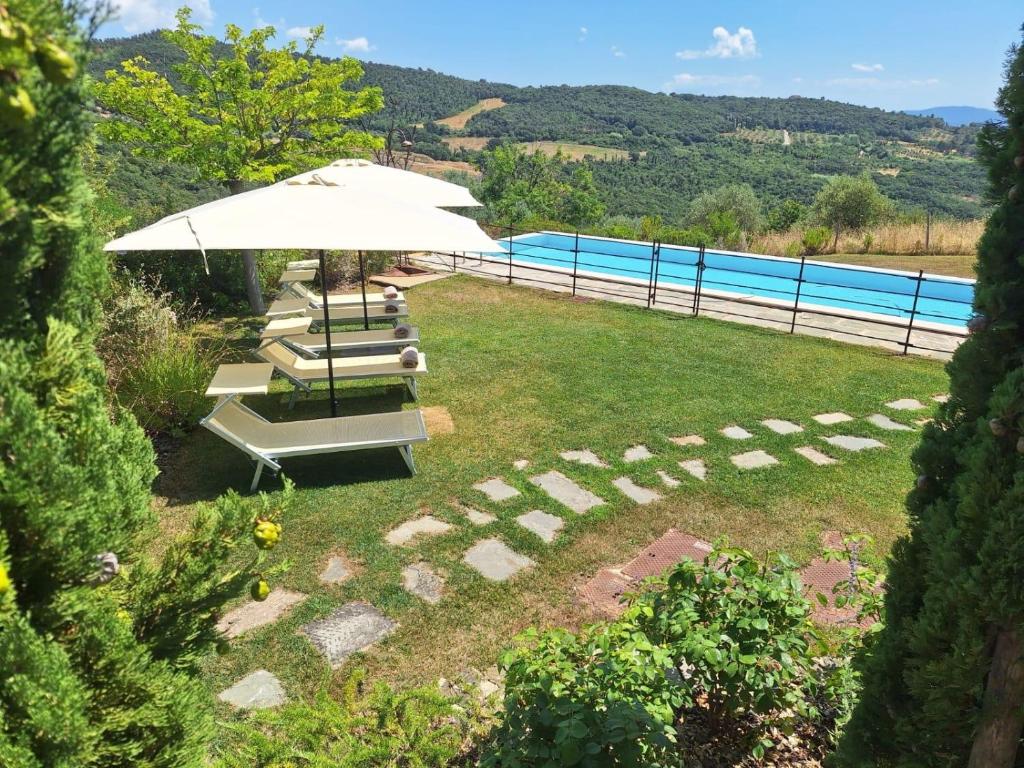 un patio avec un parasol et une piscine dans l'établissement Villa le Sughere - Privacy, Piscina e Vista Panoramica, à Castellina Marittima