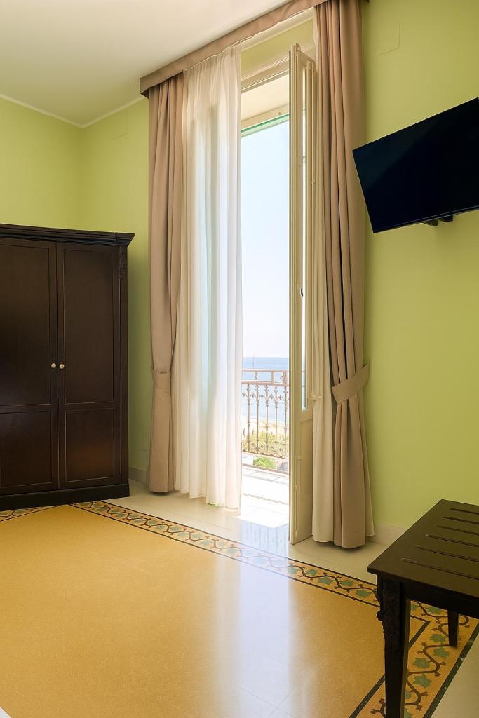 d'une chambre avec une porte coulissante en verre et une fenêtre. dans l'établissement Hotel Borgo di Ciàula, à Santa Flavia