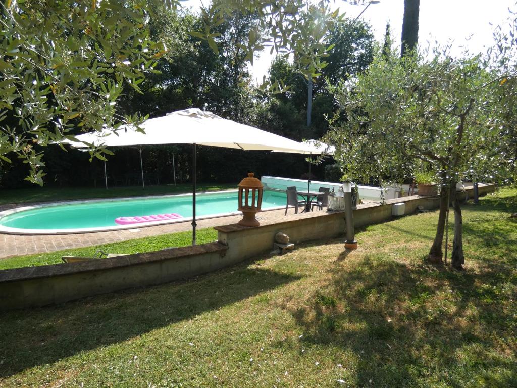 - une piscine avec un parasol, une table et des chaises dans l'établissement Scappo in Umbria, villa Claudia, à Foligno