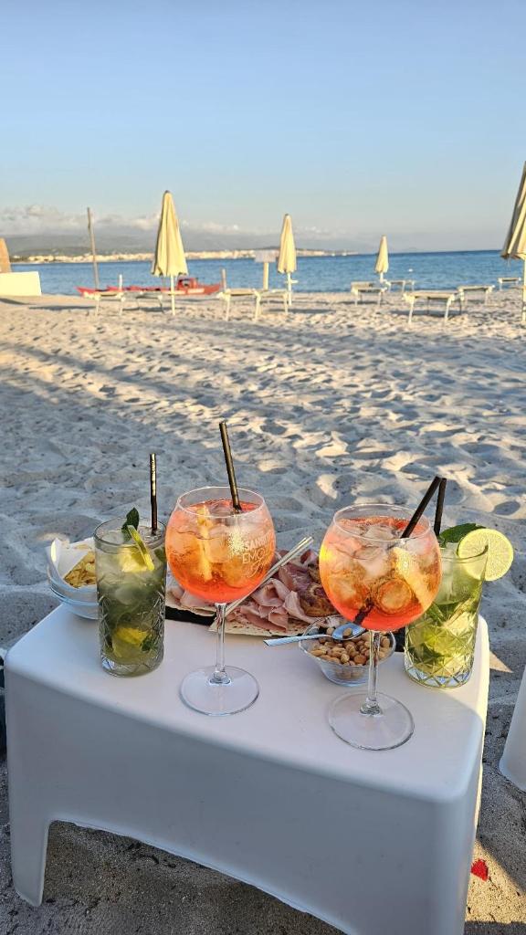 une table sur la plage avec des boissons dessus dans l'établissement Vel Marì - Rooms on the Beach, à Alghero