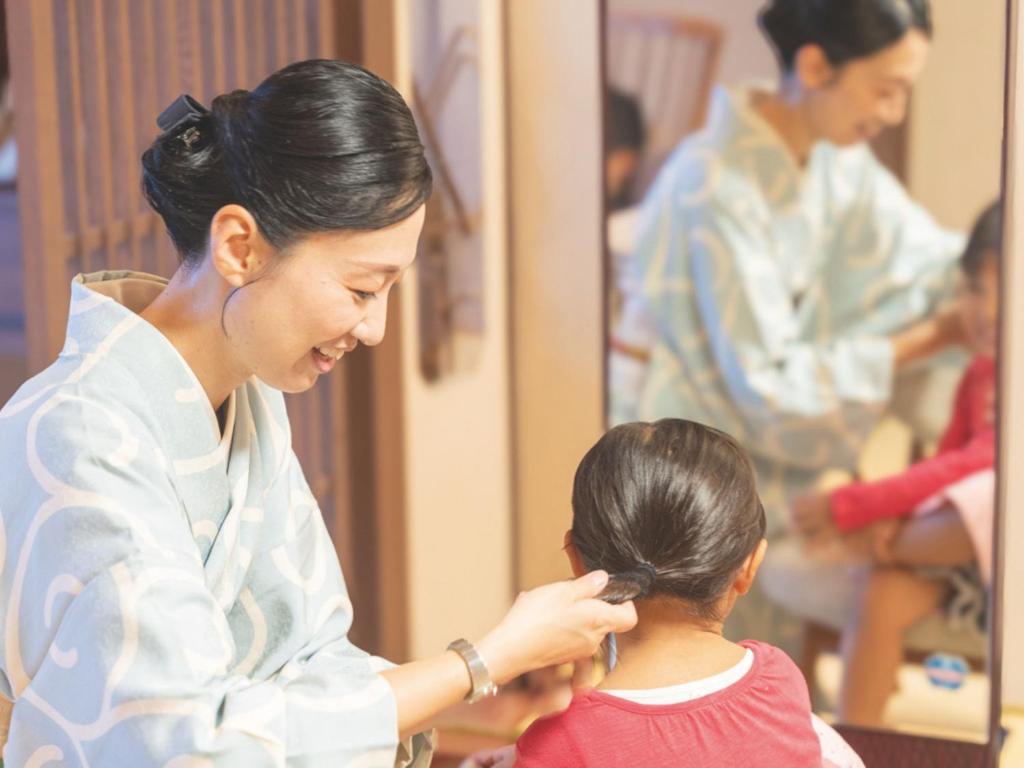 une femme peignant les cheveux d'une petite fille dans l'établissement Awakan, à Sumoto