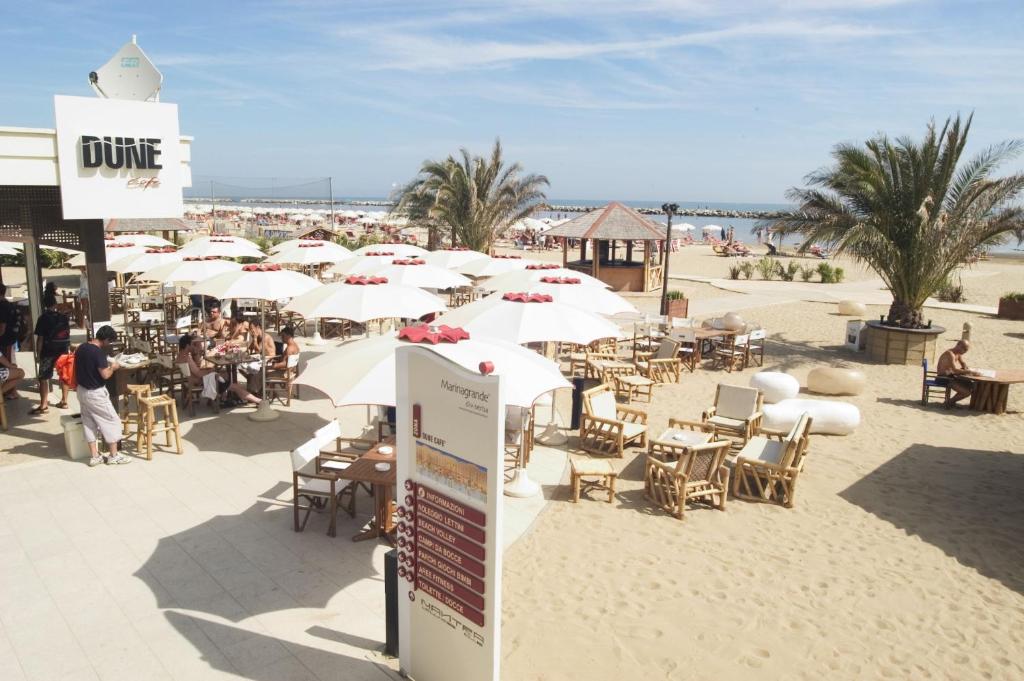 - un groupe de tables et de chaises avec parasols sur une plage dans l'établissement Apho Apartment Hotel, à Rimini