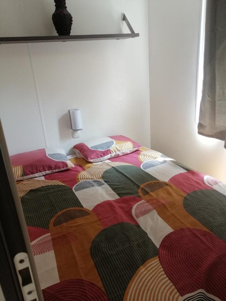 Cette chambre dispose d'un lit avec des oreillers de différentes couleurs. dans l'établissement Mobil home Chez 118 Alain, à La Roque-dʼAnthéron