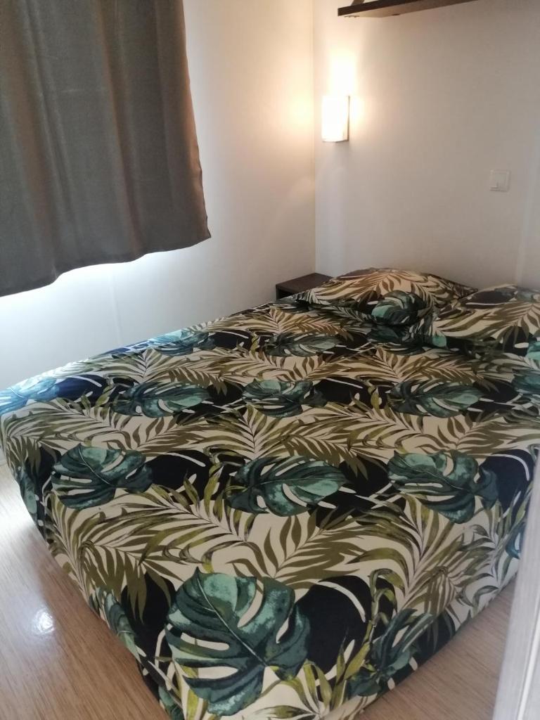 un lit avec une couette dessus dans une chambre dans l'établissement Mobil home Chez 118 Alain, à La Roque-dʼAnthéron