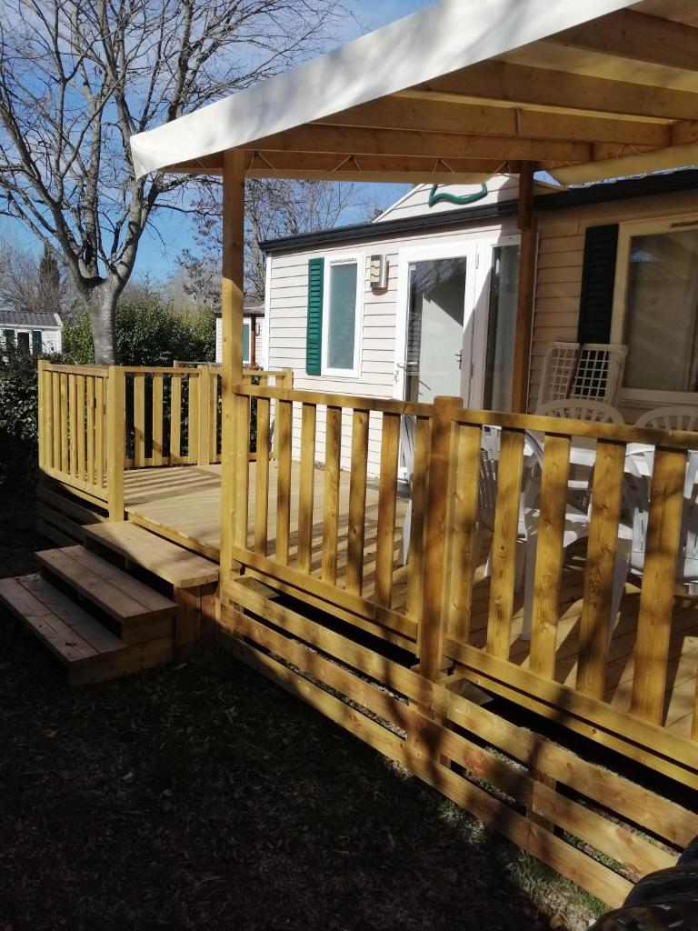 une terrasse en bois avec auvent sur une petite maison dans l'établissement Mobil home Chez 118 Alain, à La Roque-dʼAnthéron