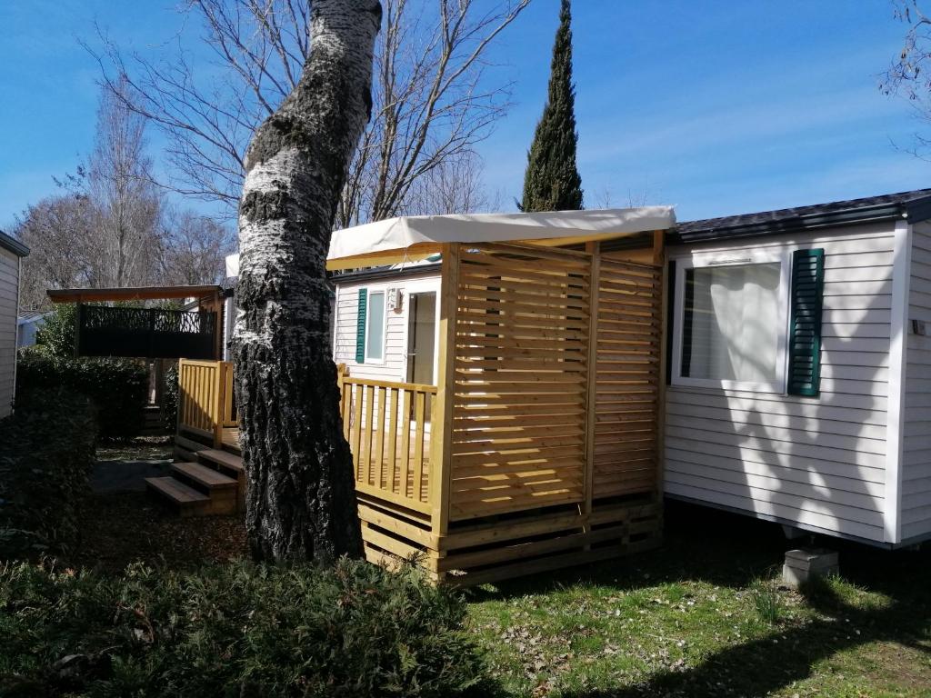une cabane en bois à côté d'un arbre dans l'établissement Mobil home Chez 118 Alain, à La Roque-dʼAnthéron