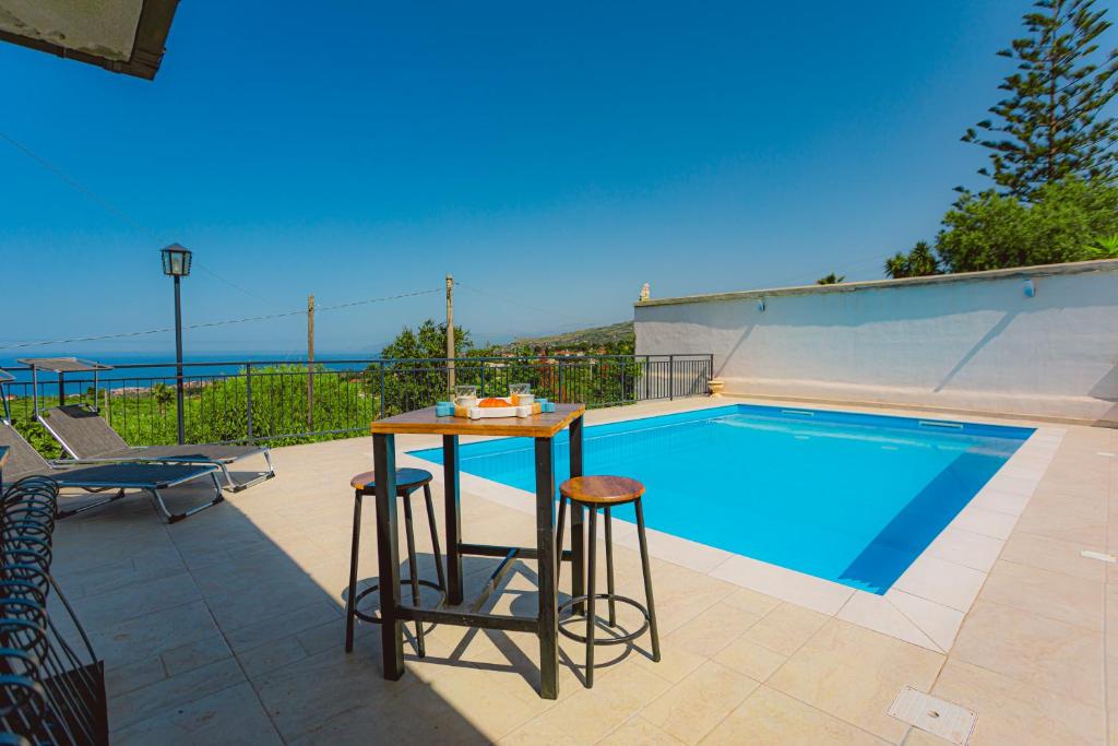 une piscine avec une table et deux tabourets à côté dans l'établissement villa ulivo rovetto, à Mandra Capreria