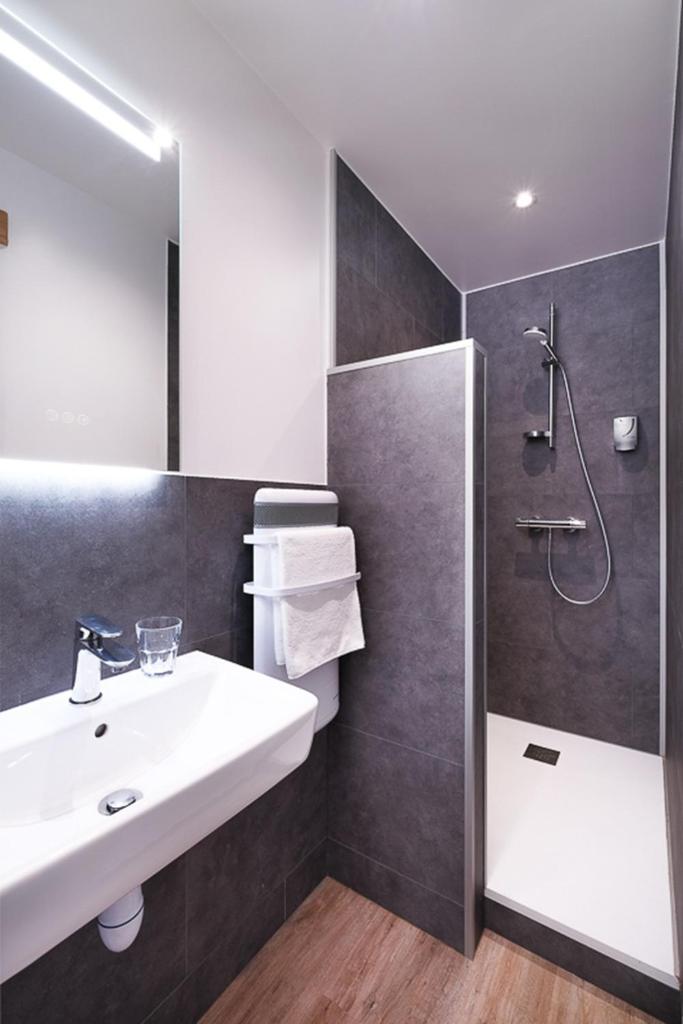 une salle de bain avec un lavabo et une douche dans l'établissement Hôtel le Christiania, à Arêches