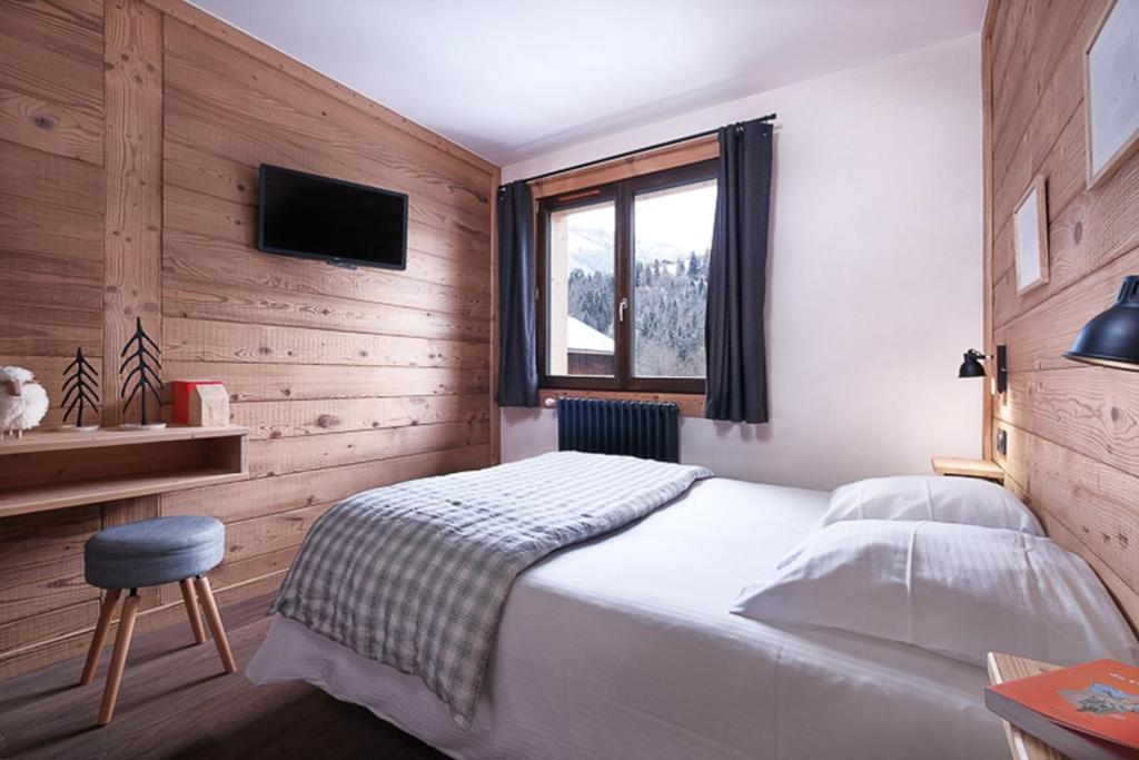 une chambre avec un lit blanc et une fenêtre dans l'établissement Hôtel le Christiania, à Arêches 8 autres photos