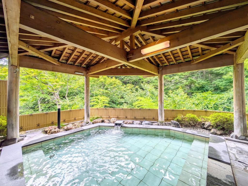 une piscine intérieure sous un grand toit en bois dans l'établissement Itoen Hotel Shima, à Nakanojo