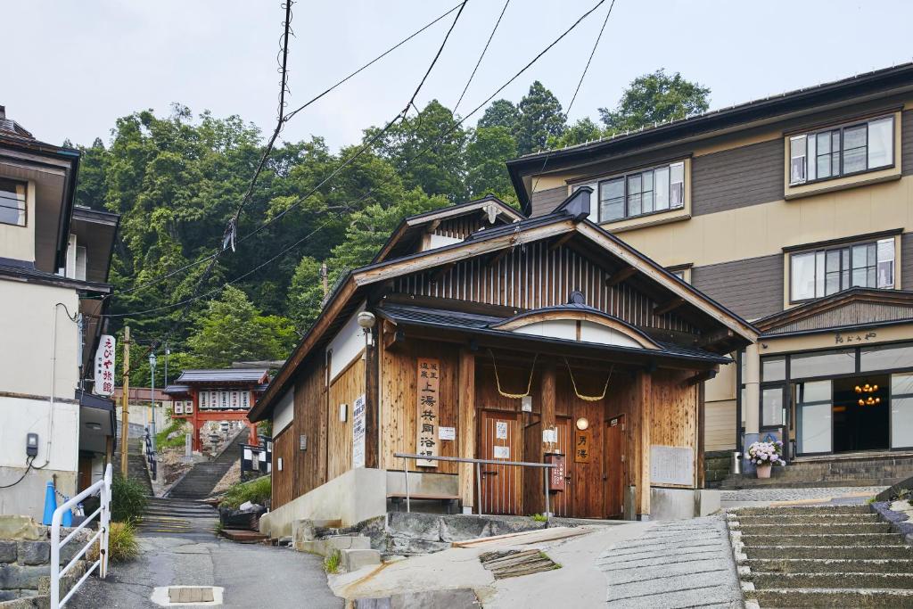 une maison avec une porte en bois dans une rue dans l'établissement 蔵王温泉 岩清水料理の宿 季の里, à Zao Onsen