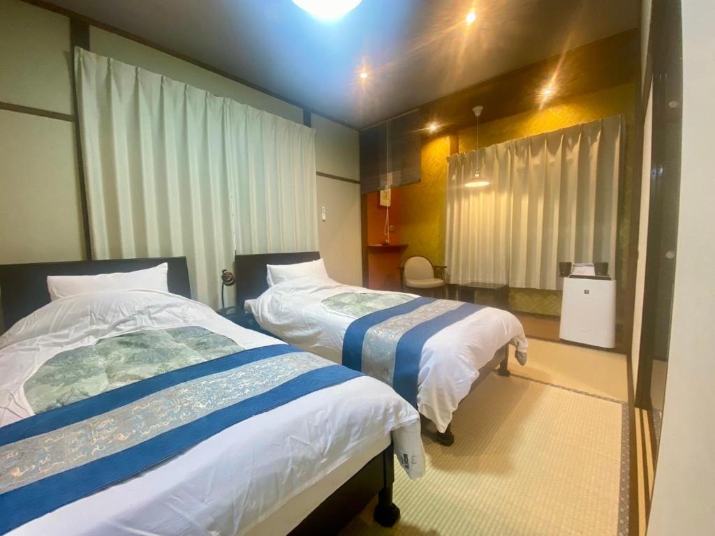 une chambre d'hôtel avec deux lits dans une chambre dans l'établissement Good Stay Mizuho, à Usa