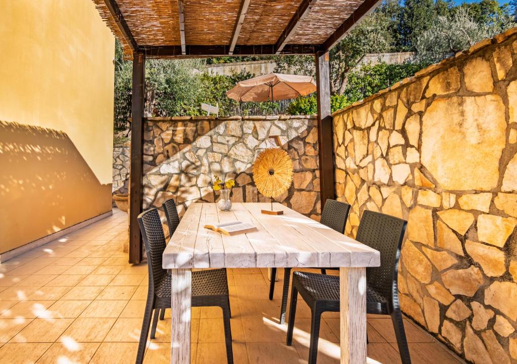 une table avec des chaises et un parasol sur un mur en pierre dans l'établissement Marelì - magnifica villa con piscina, à Livourne