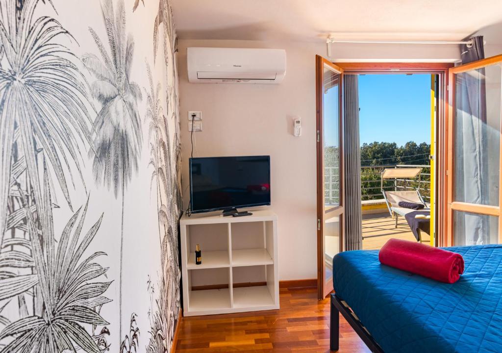 une chambre avec un canapé bleu, une télévision et un balcon dans l'établissement Marelì - magnifica villa con piscina, à Livourne