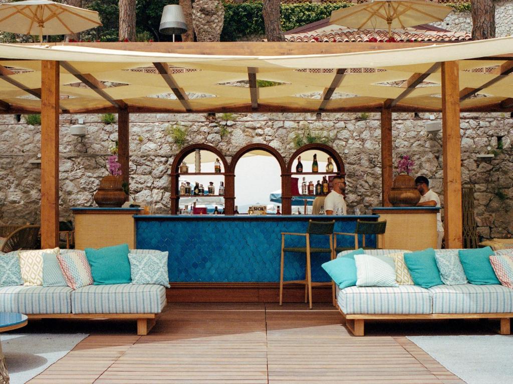 un patio avec deux canapés et un bar dans l'établissement Villa Sant'Andrea, A Belmond Hotel, Taormina Mare, à Taormine