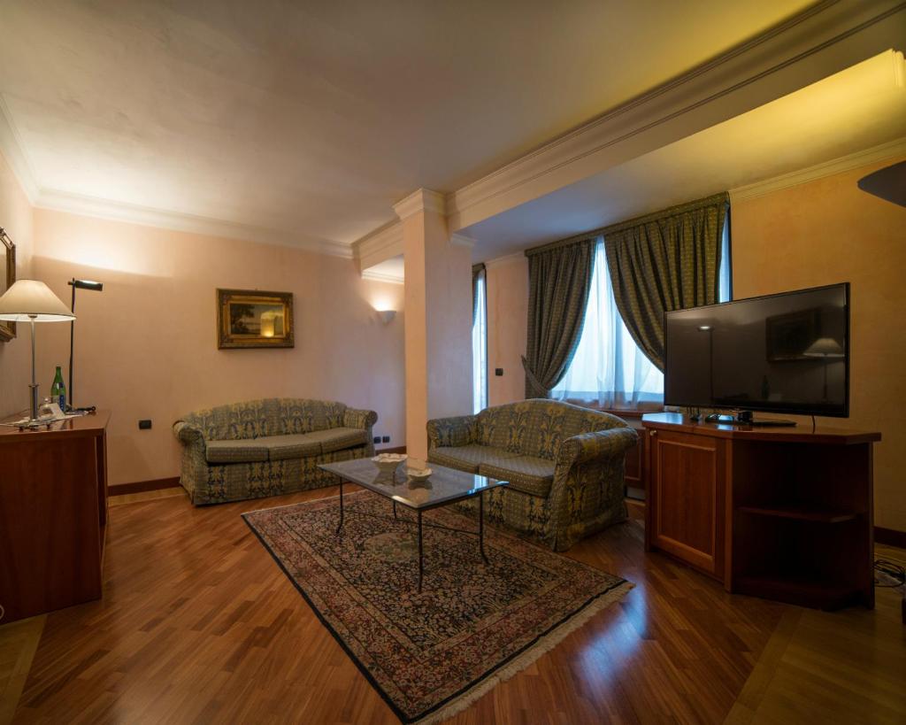 un salon avec un canapé et une télévision dans l'établissement Hotel Nettuno, à Catane