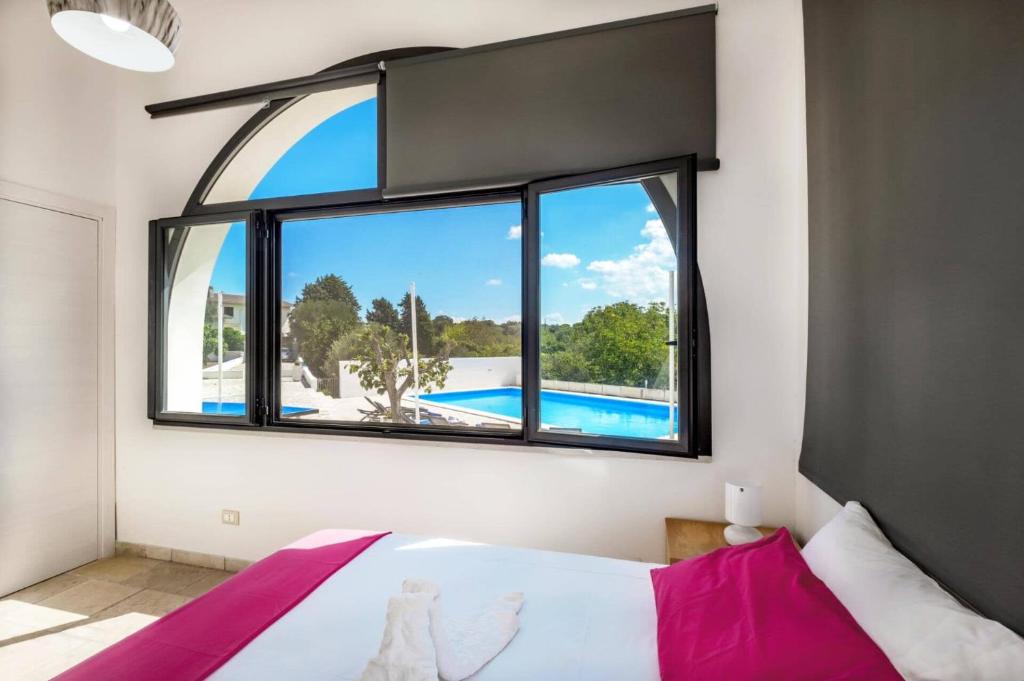 une chambre avec une grande fenêtre avec une piscine à l'extérieur dans l'établissement Villa Azzurrato by Villa Plus, à Ceglie Messapica 32 autres photos