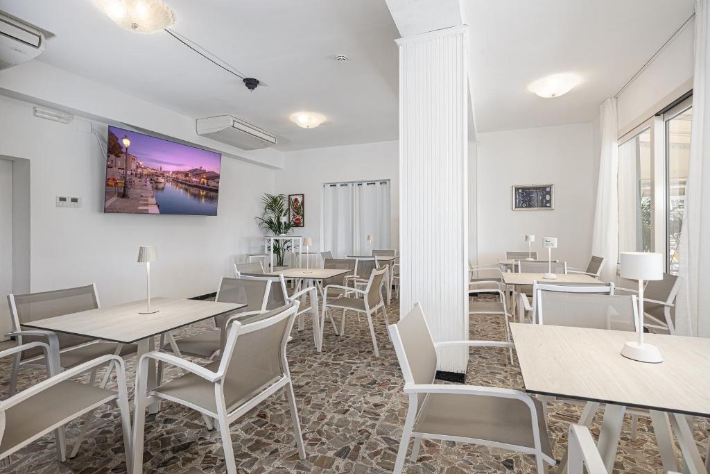 un restaurant avec des tables et des chaises blanches et des fenêtres dans l'établissement Hotel Altamarea Cesenatico, à Cesenatico 23 autres photos