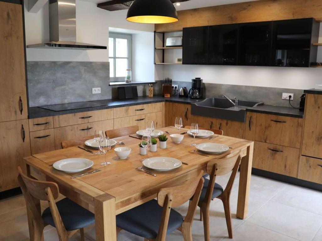 - une cuisine avec une table en bois, des assiettes et des verres à vin dans l'établissement Gîte 18ème rénové avec piscine couverte, terrasse, loisirs et WiFi – 6 pers. - FR-1-426-432, aux Herbiers