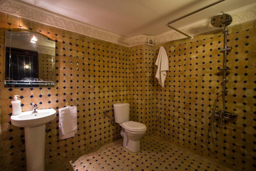 une salle de bain avec un lavabo, des toilettes et un miroir dans l'établissement Dar El Mathaf, à Fès