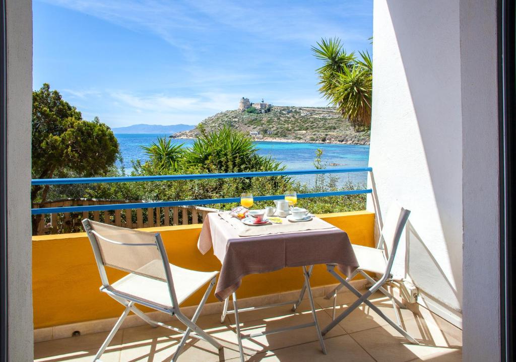 une table et des chaises sur un balcon avec vue sur l'océan dans l'établissement Hotel Calamosca, à Cagliari
