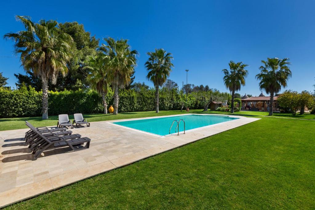 une piscine avec deux chaises longues et des palmiers dans l'établissement Tenuta Bouganville by Perle di Puglia, à Francavilla Fontana