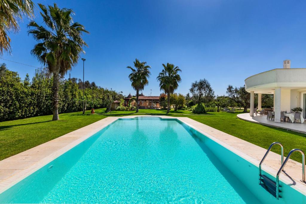 - une piscine dans l'arrière-cour d'une maison avec des palmiers dans l'établissement Tenuta Bouganville by Perle di Puglia, à Francavilla Fontana